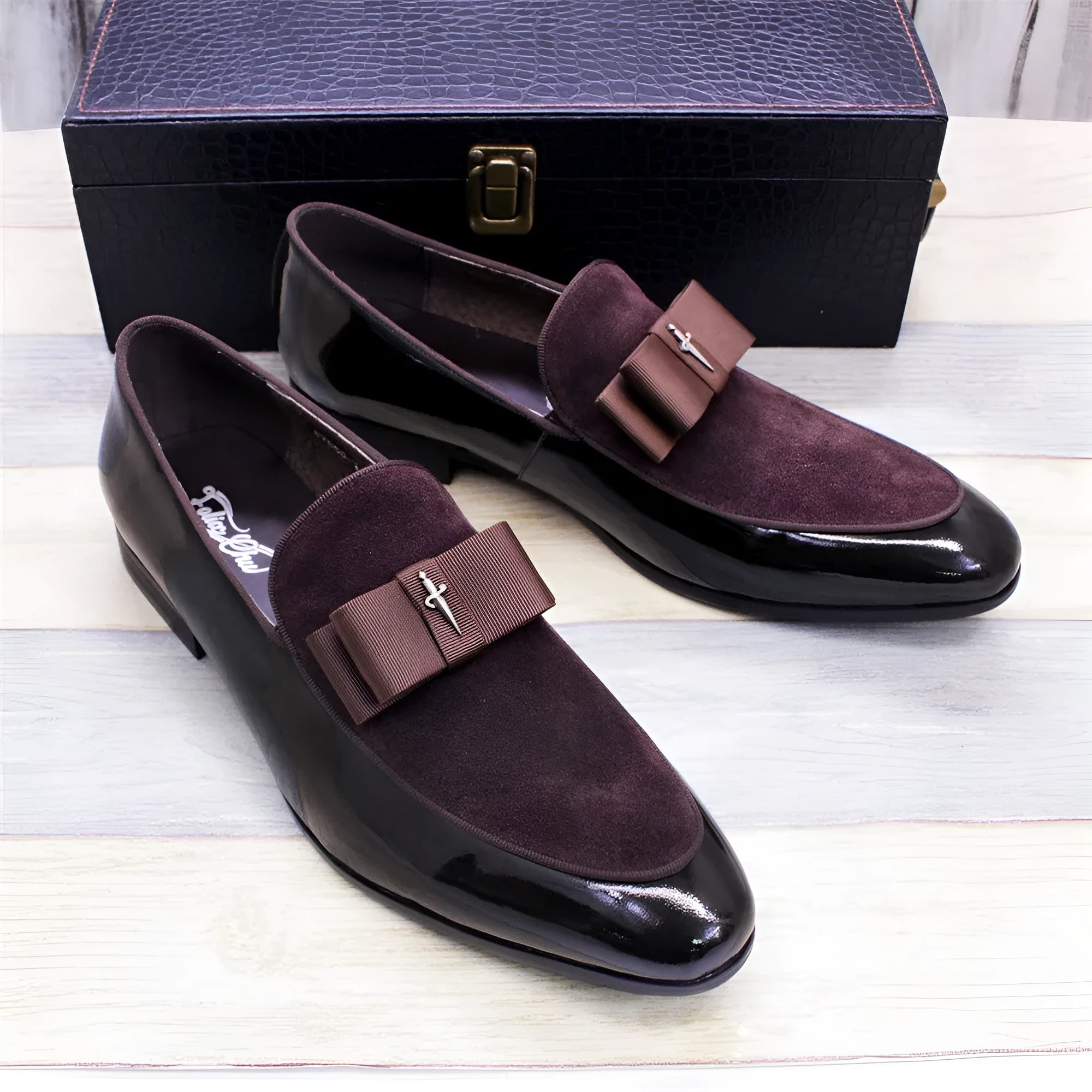 Men's glossy black patent leather low-top shoes featuring a gold tassel detail on a white background.
