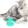 Rotating windmill cat toy with LED light and catnip balls on a white wall