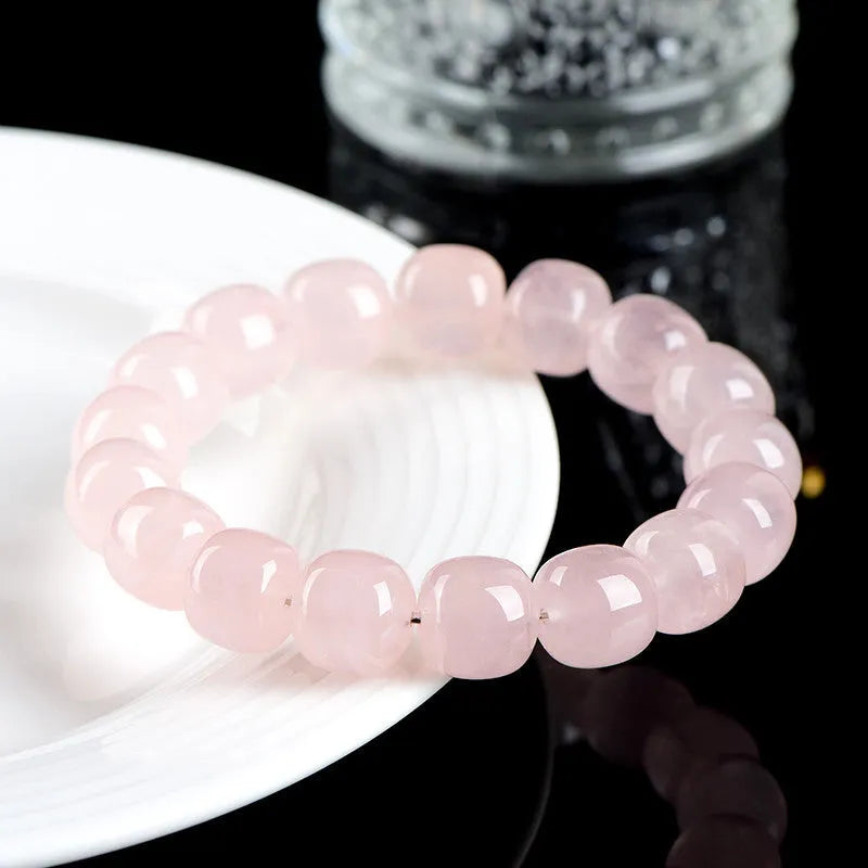 Close-up of a pink crystal bracelet with barrel-shaped beads on a wrist.