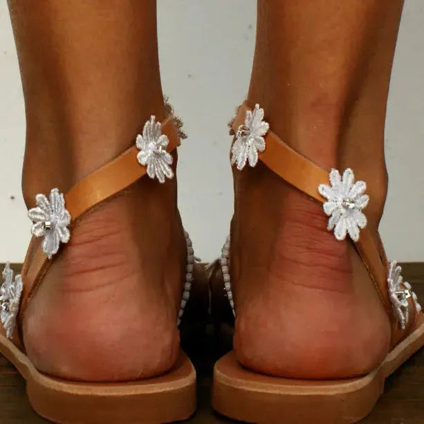 Brown women's Roman sandals with floral pattern, flat rubber sole, and herringbone toe design.
