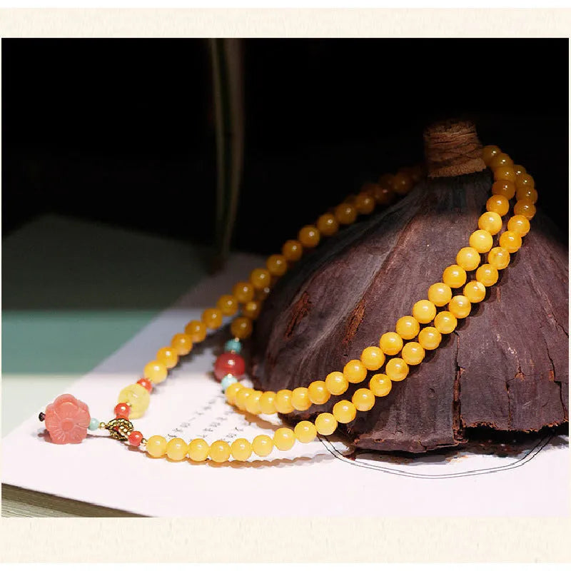 Yellow chicken grease coloured amber bracelet with animal zodiac charm on a white background.