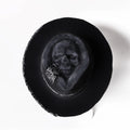 Handmade black and white skull print pointed witch hat on a wooden surface