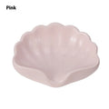 A white or pink plastic shell-shaped soap dish for bathroom counter or shower use.