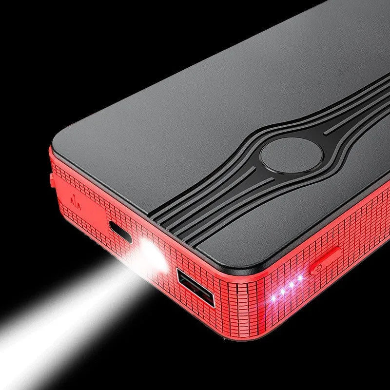 Red K4-E automobile emergency jump starter power supply unit with a USB cable on a table.