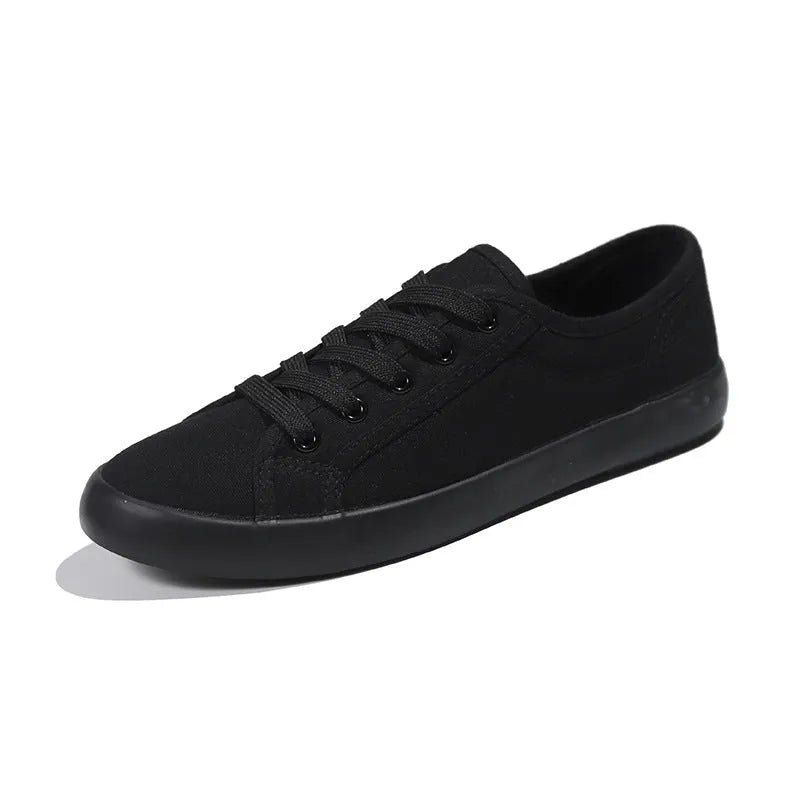 Women's all-black canvas flat lace-up shoes with a slim profile and rubber sole.