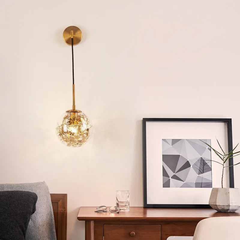 Modern simple glass bedside wall lamp in silver or gold finish on a white wall.