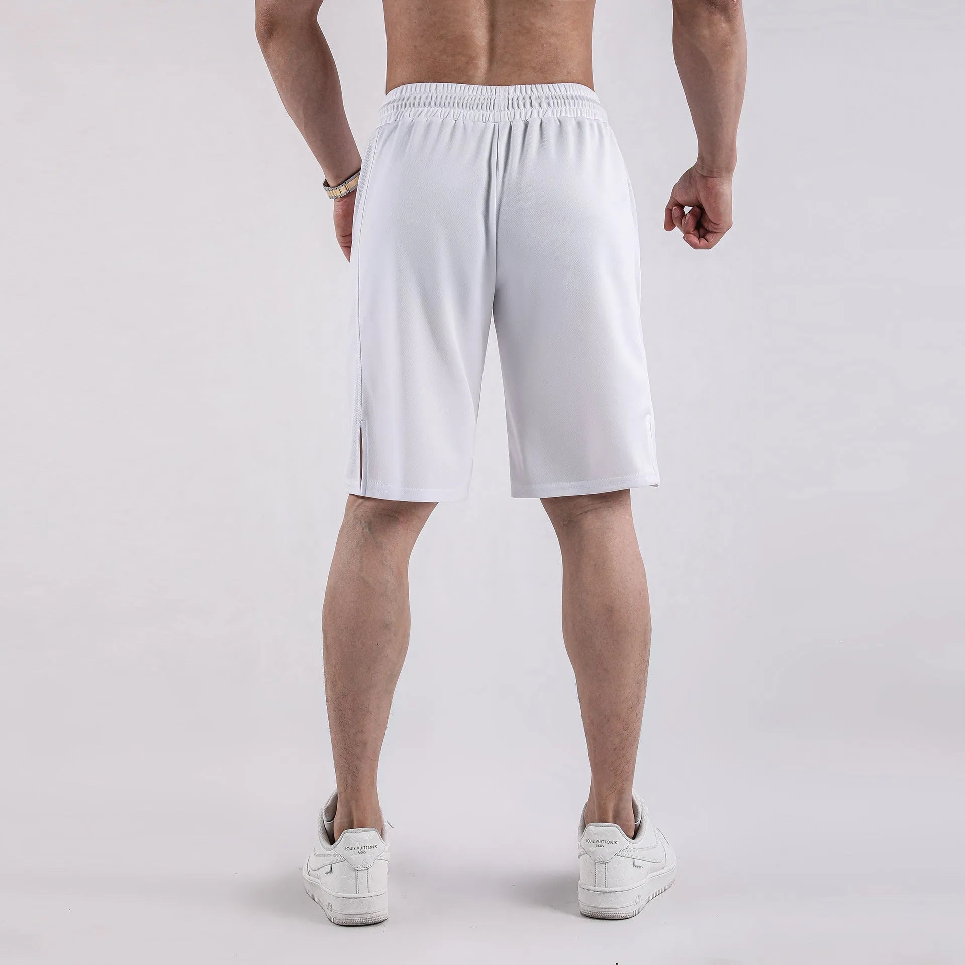 Man wearing black quick-drying mesh fitness shorts with an elastic mid-waist and loose fit.