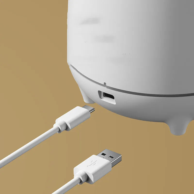 White volcano-shaped humidifier and aromatherapy diffuser on a table with USB cable.
