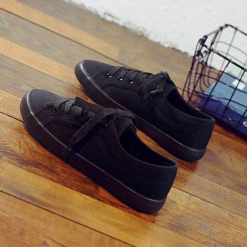 Women's all-black canvas flat lace-up shoes with a slim profile and rubber sole.