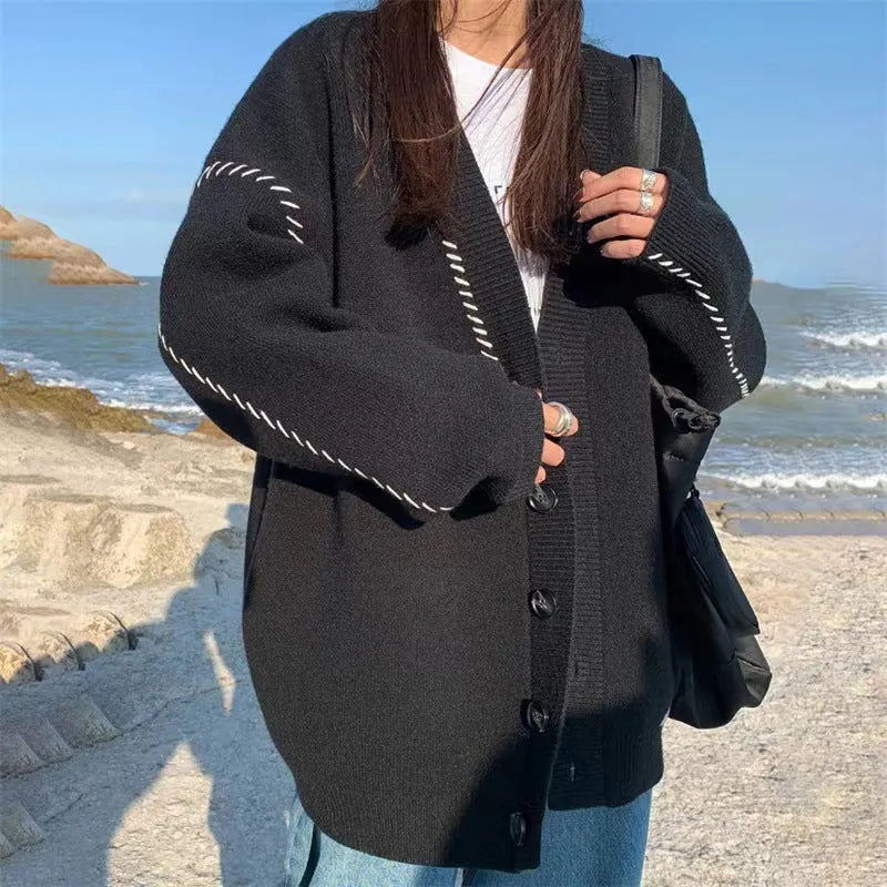 Women's loose-fit black knitted cardigan top coat with long sleeves on a hanger.