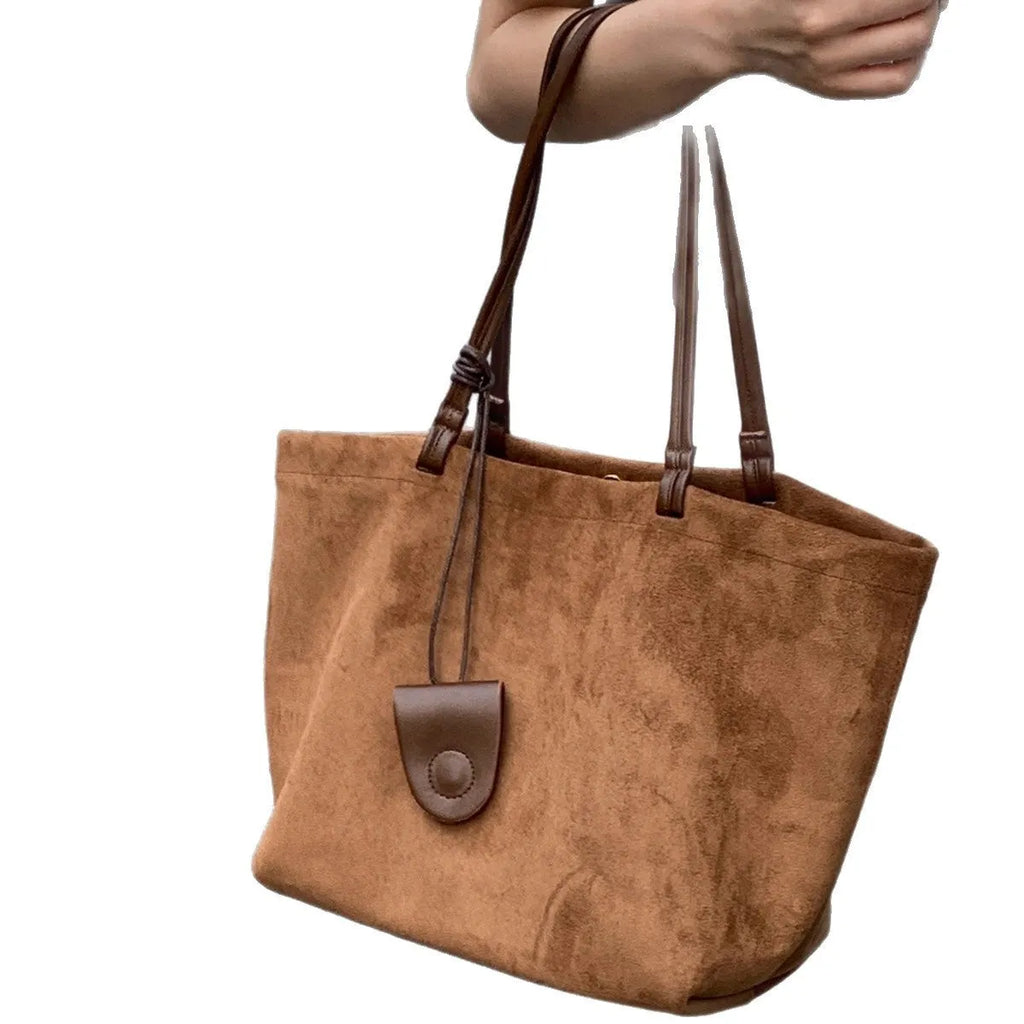Brown suede shoulder bag with double straps and sewing line detail on a white background