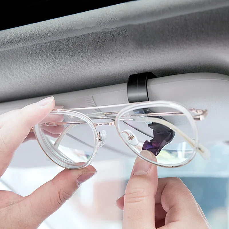 Black plastic multifunctional clip for car sunshades, holding sunglasses and a card.