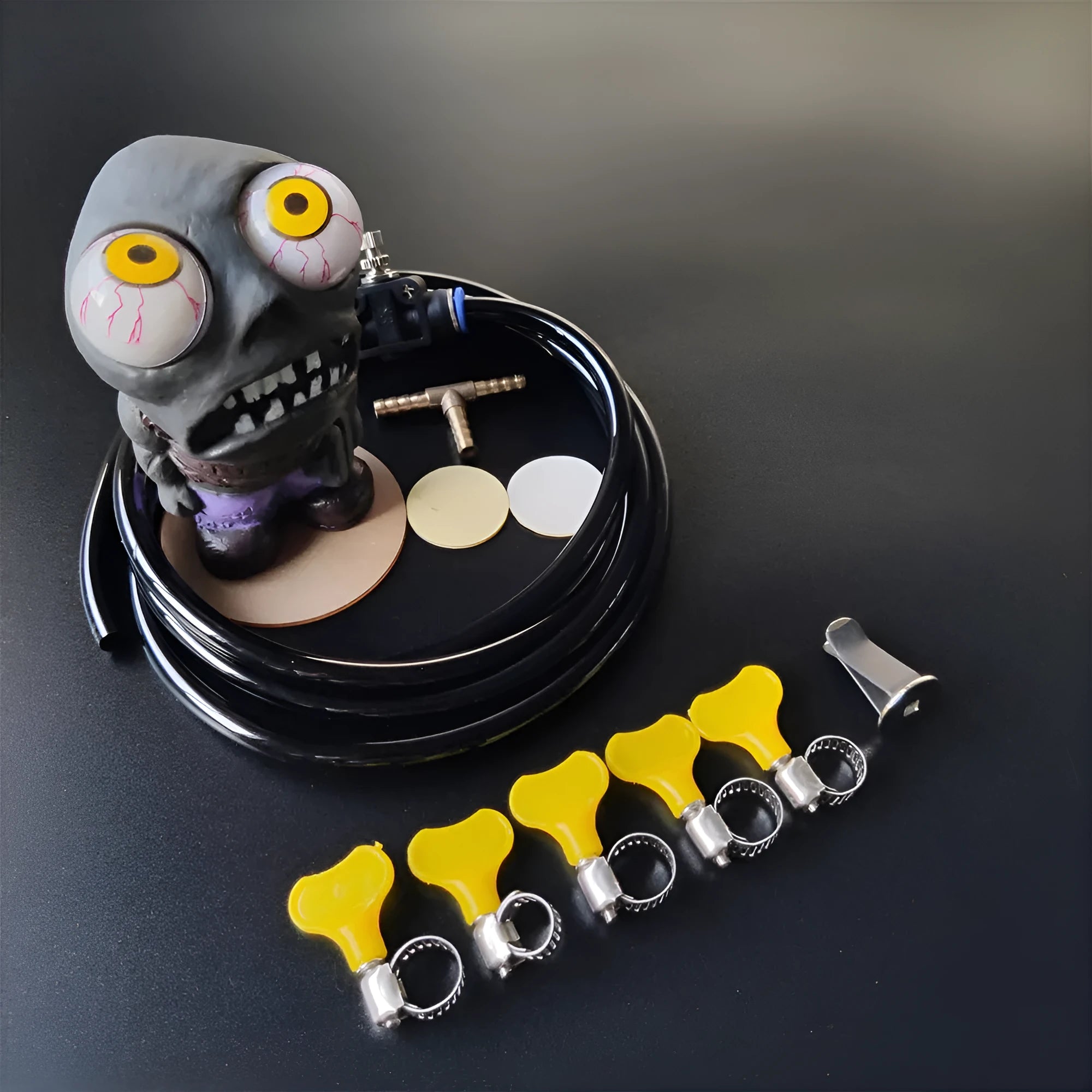 Turbo car blow-off valve pressure release kit showing rubber doll ornament, copper tube, pressure valve, and clips.