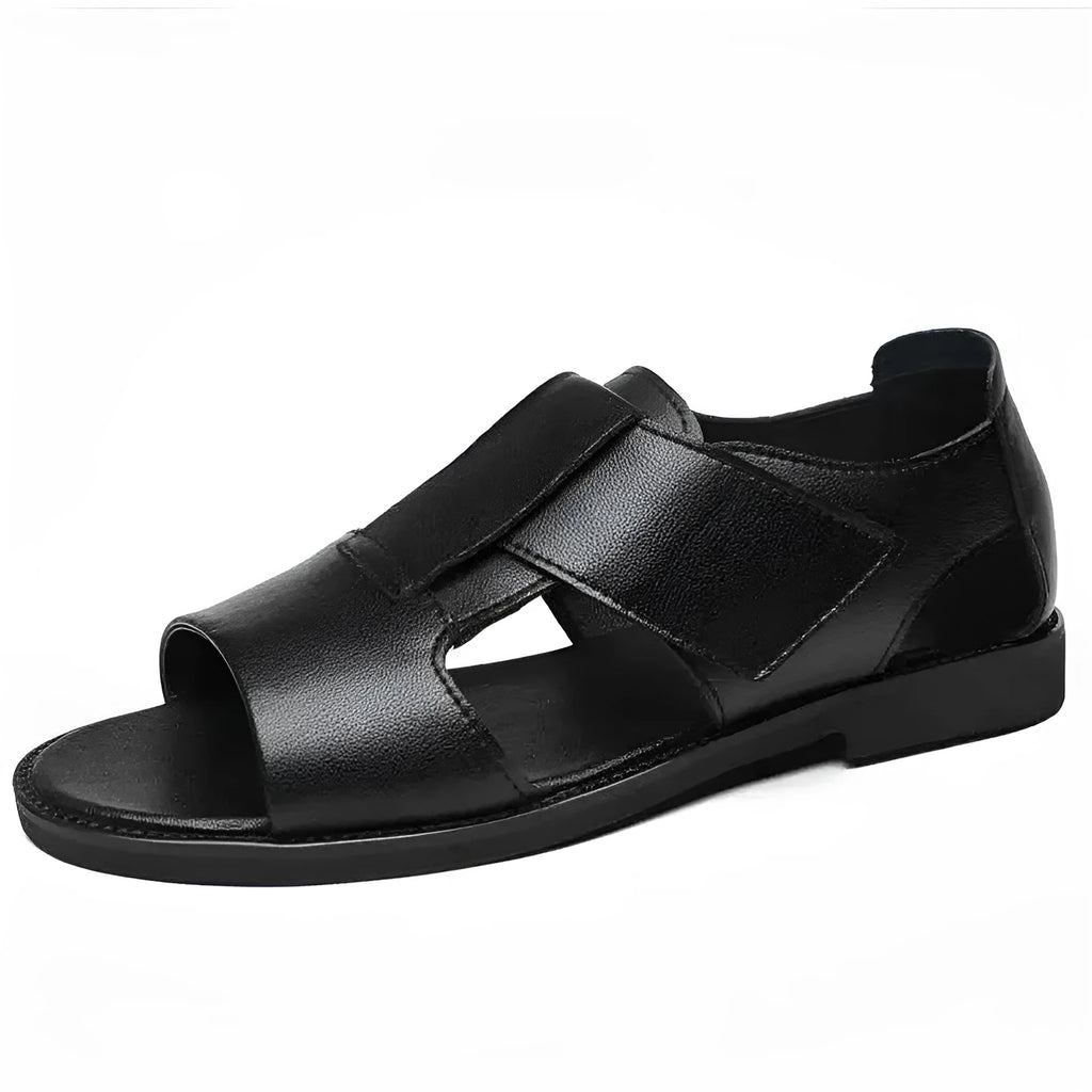 Men's black leather Roman sandals with open toe and non-slip rubber sole on a sandy beach.