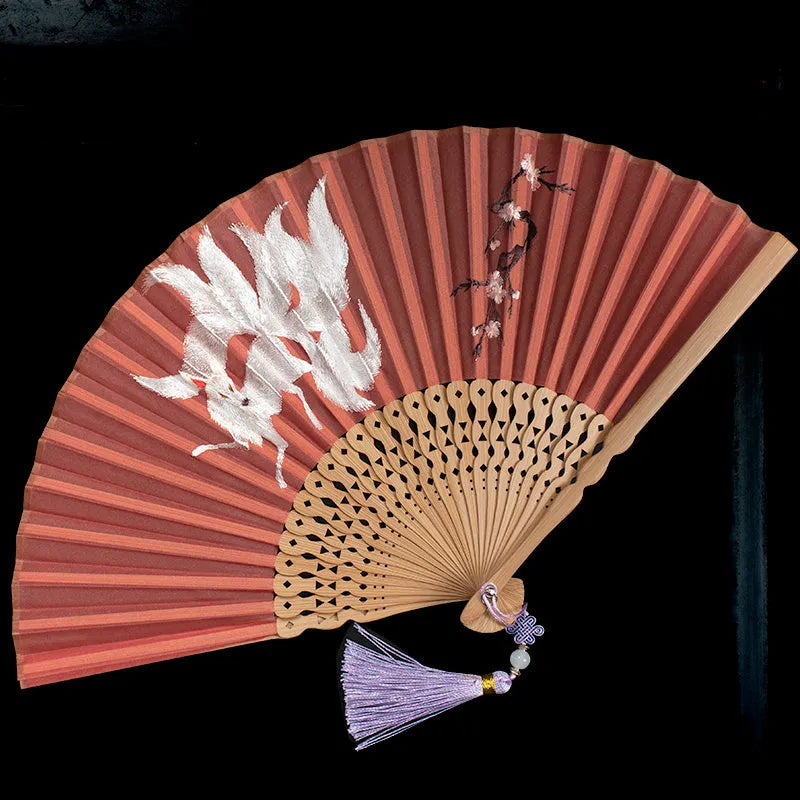 Close-up of a traditional Chinese folding fan with intricate embroidery on a bamboo frame.