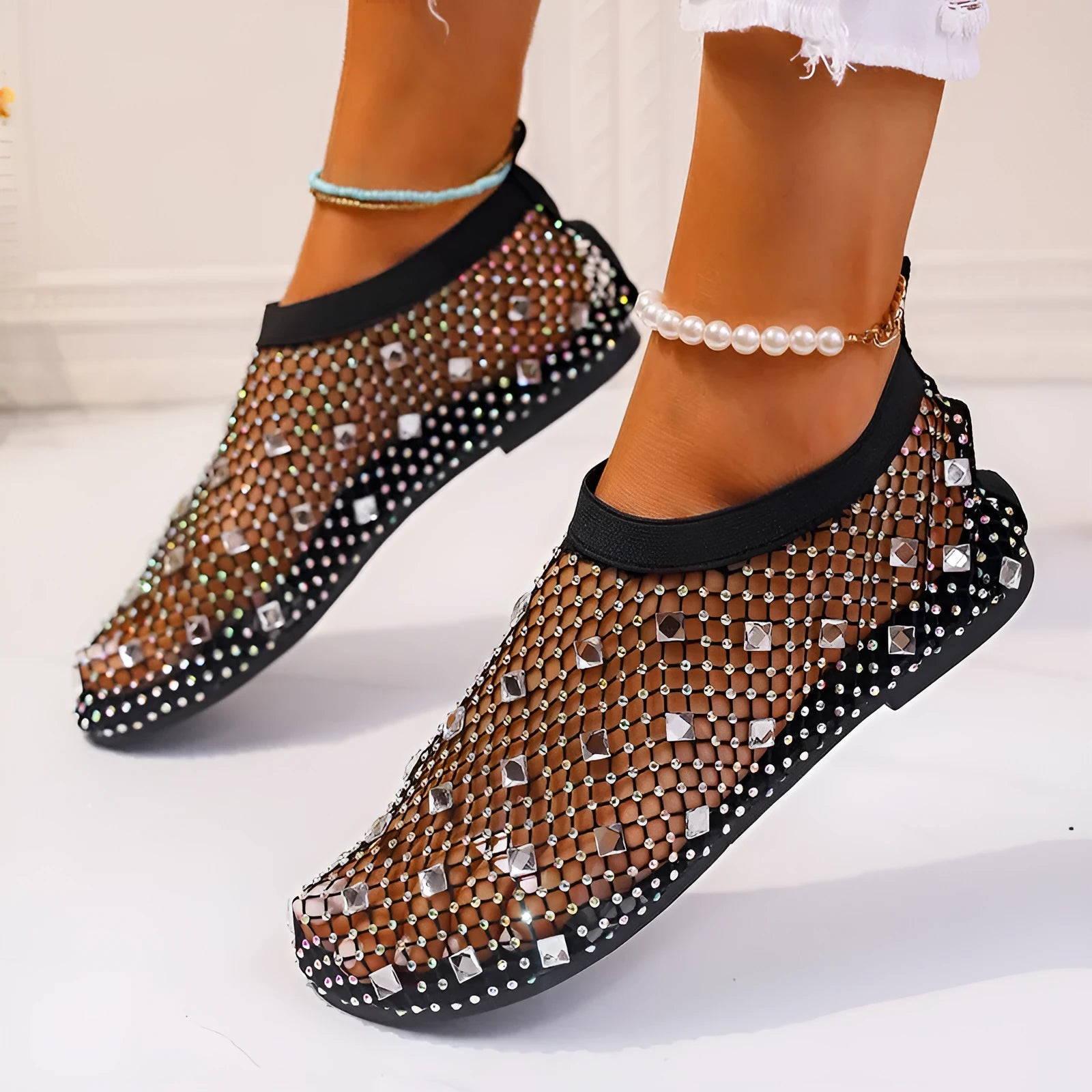 Women's flat sandals with colourful rhinestones on a breathable mesh upper and rubber sole.