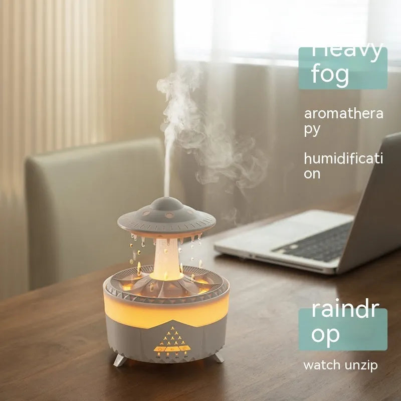 White cloud-shaped humidifier with water droplets and coloured lights on wooden surface