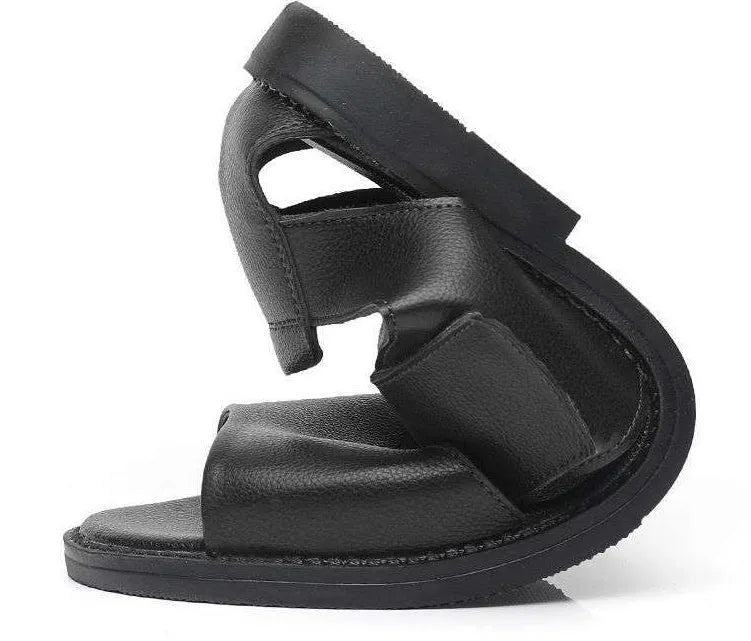 Men's black leather Roman sandals with open toe and non-slip rubber sole on a sandy beach.