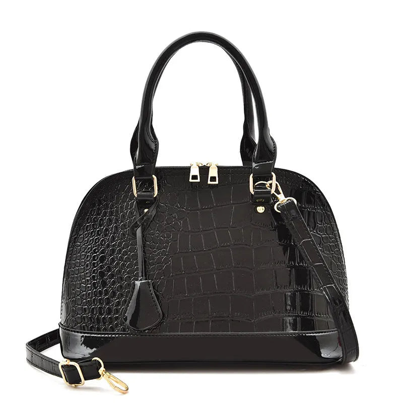 Large shiny black PU leather crossbody bag with shell suitcase shape on a model