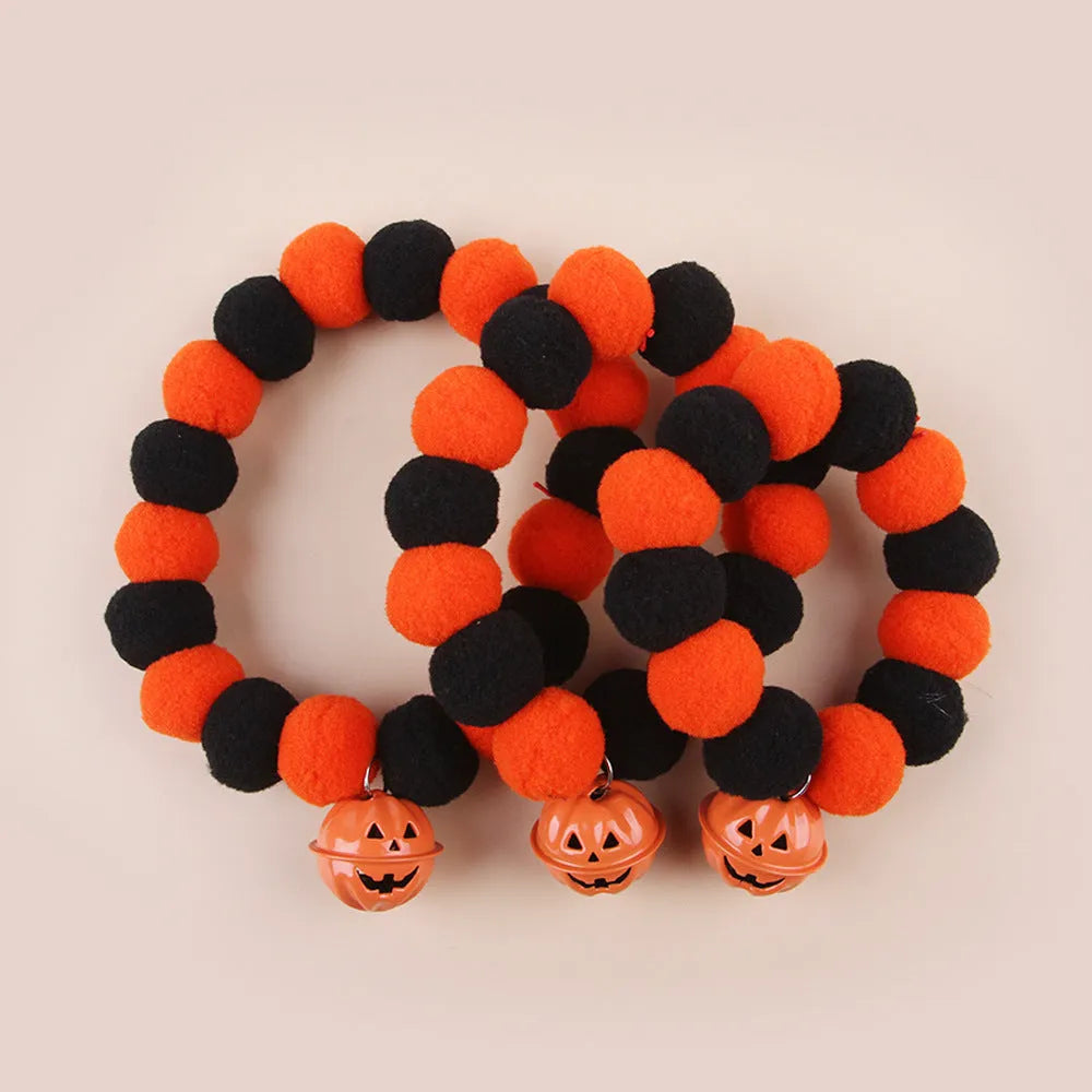 Orange Halloween cat collar with plastic pumpkin, ghost, and bat charms on a black strap.