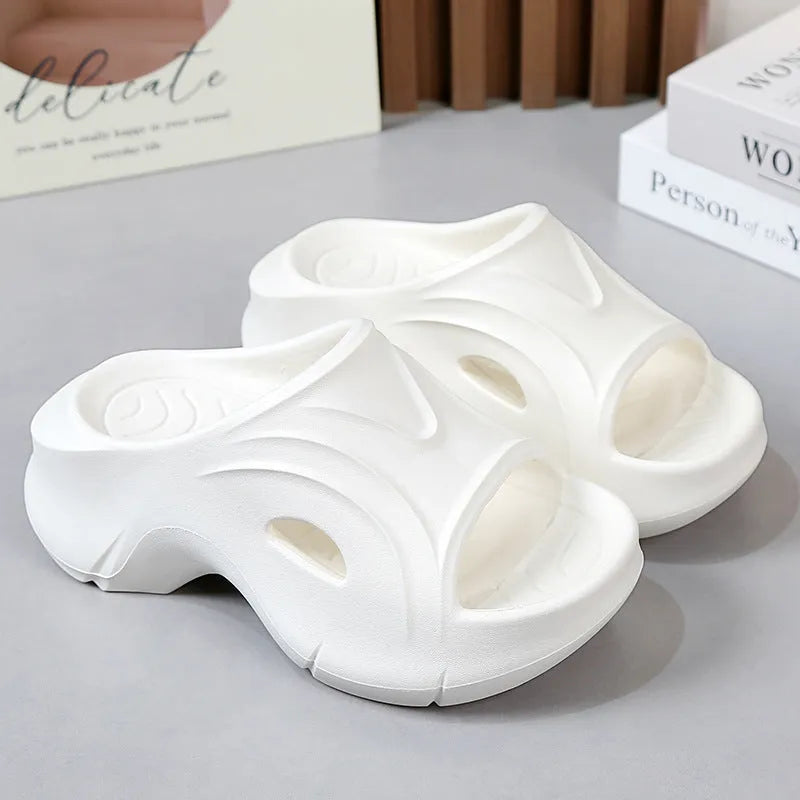 Women's white thick-soled EVA slippers on a sandy beach background.