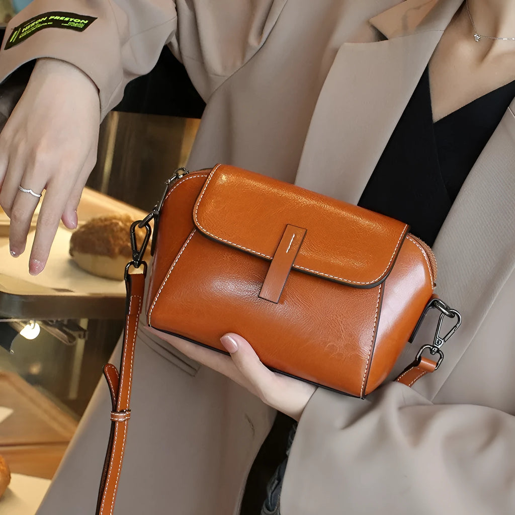 Women's brown oil wax leather shell-shaped messenger bag with a cross-body strap and front sandwich pocket.