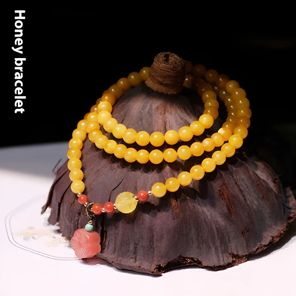 Yellow chicken grease coloured amber bracelet with animal zodiac charm on a white background.