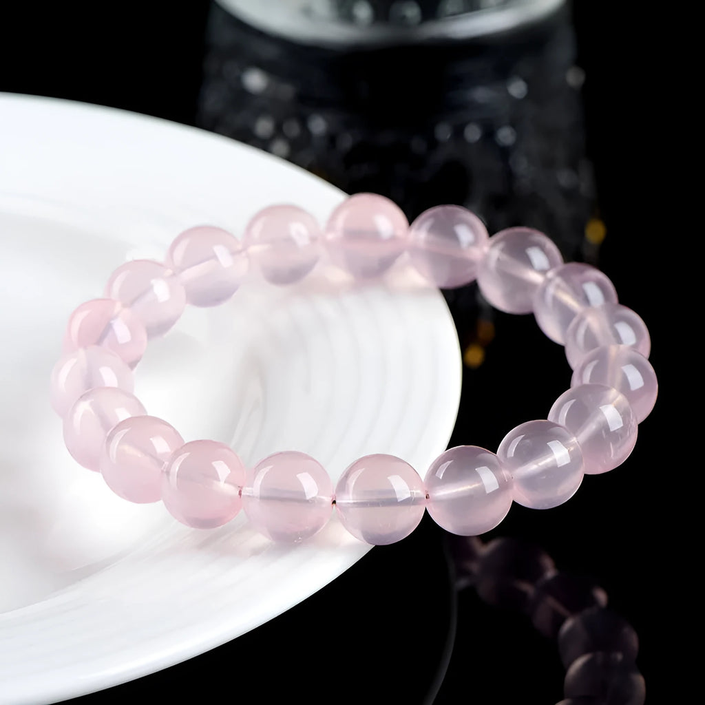 Women's pink polished crystal round bead bracelet in natural starlight style on a white background.