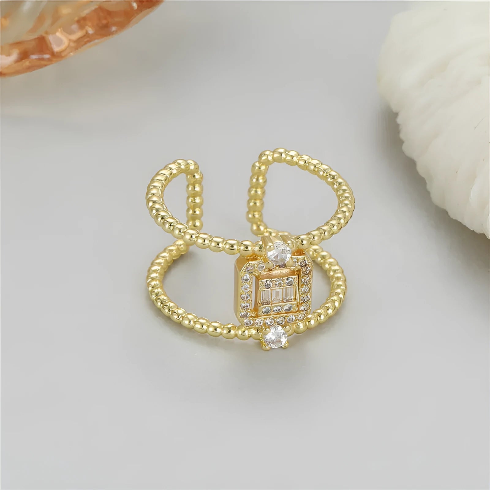 Gold-coloured asymmetric U-shaped open ring with an adjustable opening on a neutral background.