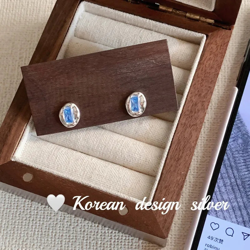 S925 sterling silver earrings with oval blue diamond heart-wrapped geometric design and electroplated silver finish