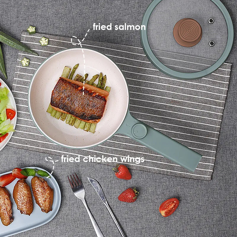 White and green multi-function electric cooking pot with temperature control dial, shown with a UK plug converter.