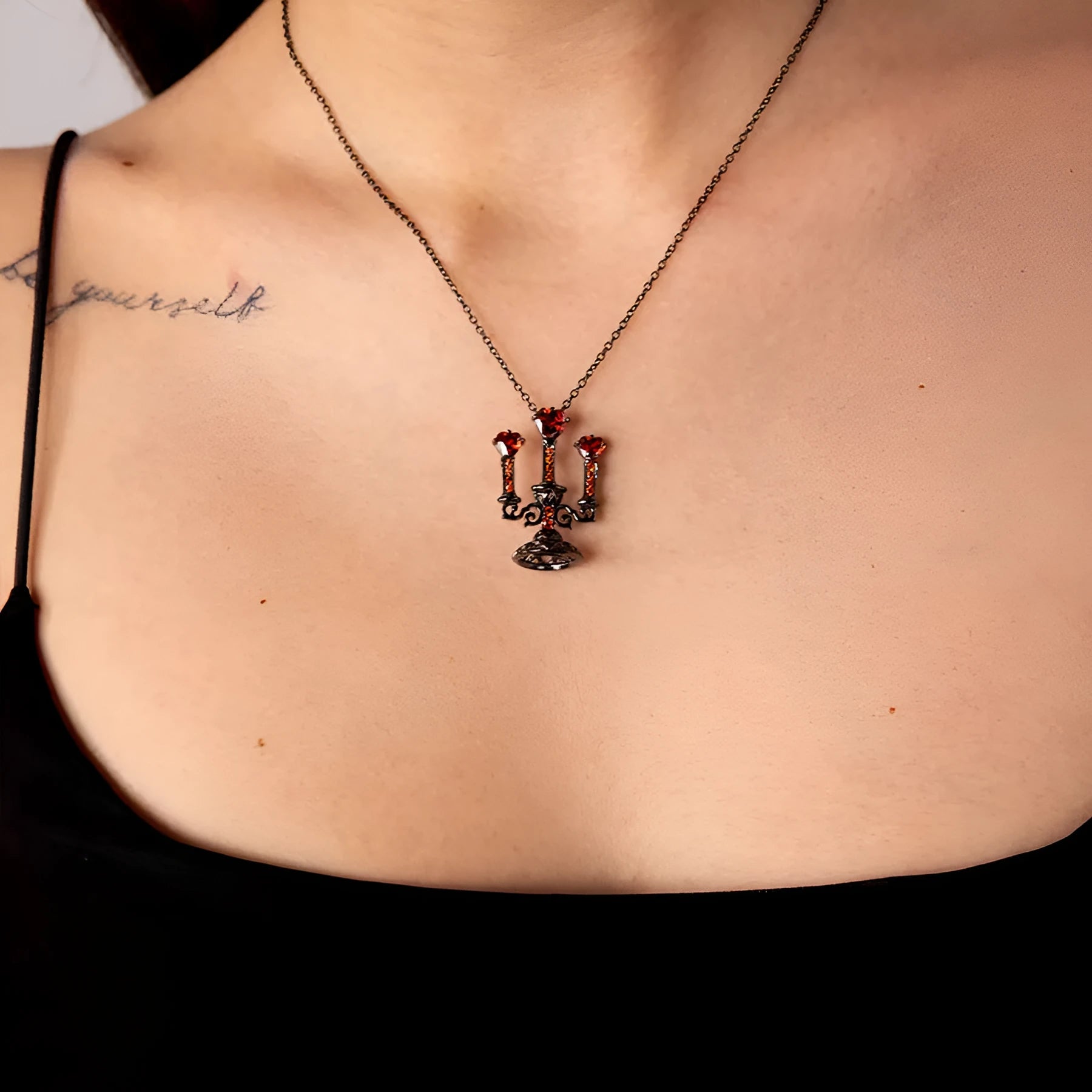 Close-up of a women's retro gothic necklace with a hollow candlestick pendant on a cross chain.