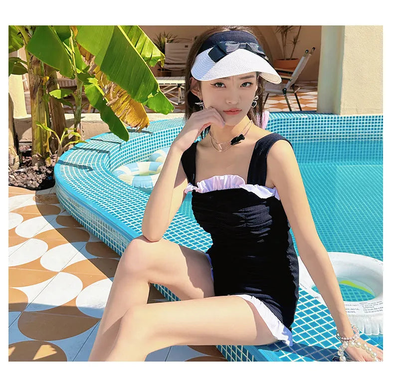 Women's solid pink one-piece swimsuit with black suspender straps on a mannequin.