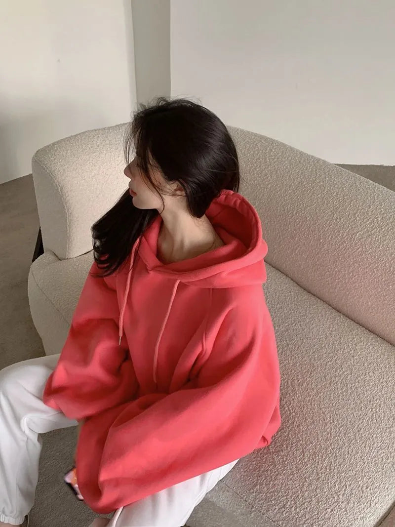 Watermelon red women's sleeveless silk hooded sweater on a hanger showing loose fit and hood detail.