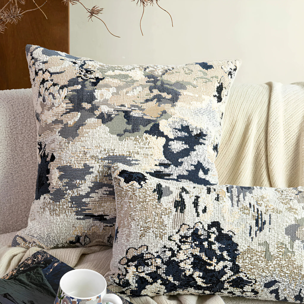 Blue abstract floral patterned decorative pillow on a sofa, showing square and rectangular sizes.