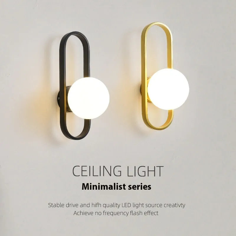 Minimalist black iron wall lamp with a glass shade mounted on a white wall.
