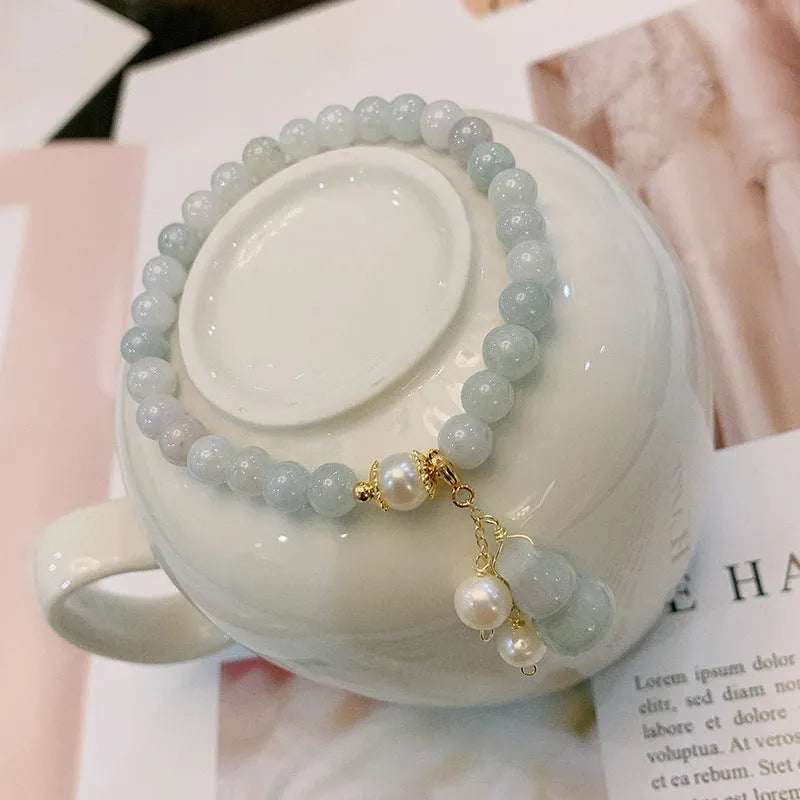 Women's handmade jade bracelet with traditional gourd charm design and pearl accents in natural emerald green colour
