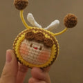Handmade crocheted plush bee hive and bees accessory for woolen dolls on a white background.