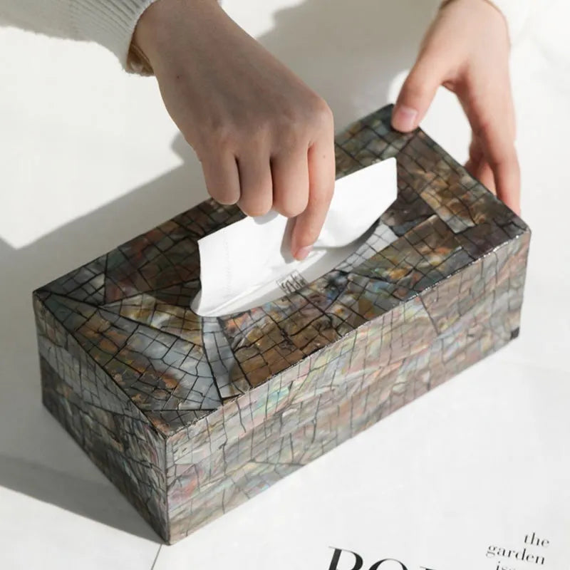 A black square shell storage box with a removable organiser insert on a coffee table.