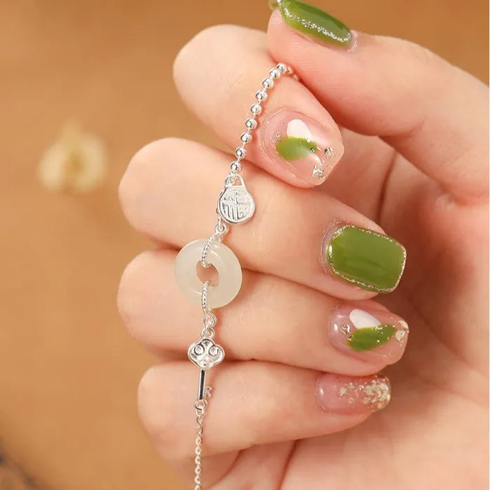 Women's Chinese style silver bracelet with a Hetian jade stone and intricate Peace Buckle design.
