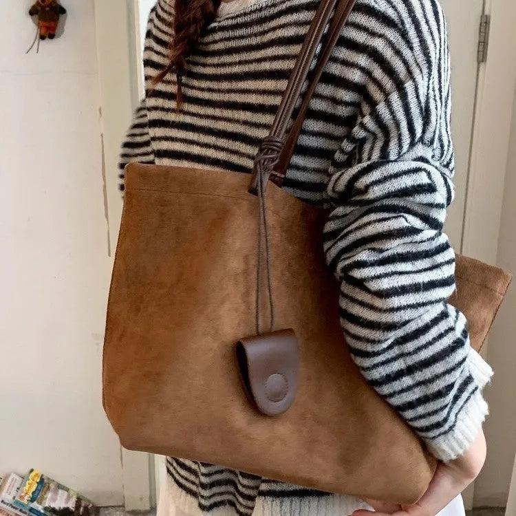 Brown suede shoulder bag with double straps and sewing line detail on a white background