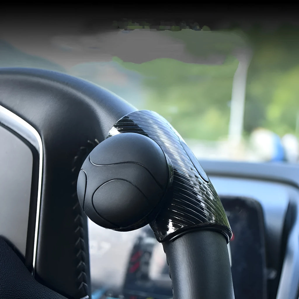 Black silicone steering wheel assist ball with metal bearing for single-handed driving aid.