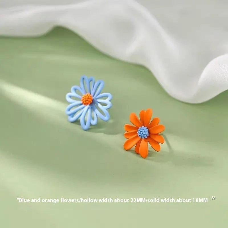 Close-up of colourful alloy flower stud earrings showing white and green two-tone design.