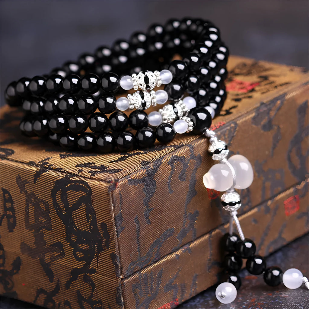 Black agate bracelet with 108 geometric beads and number details on a wrist.