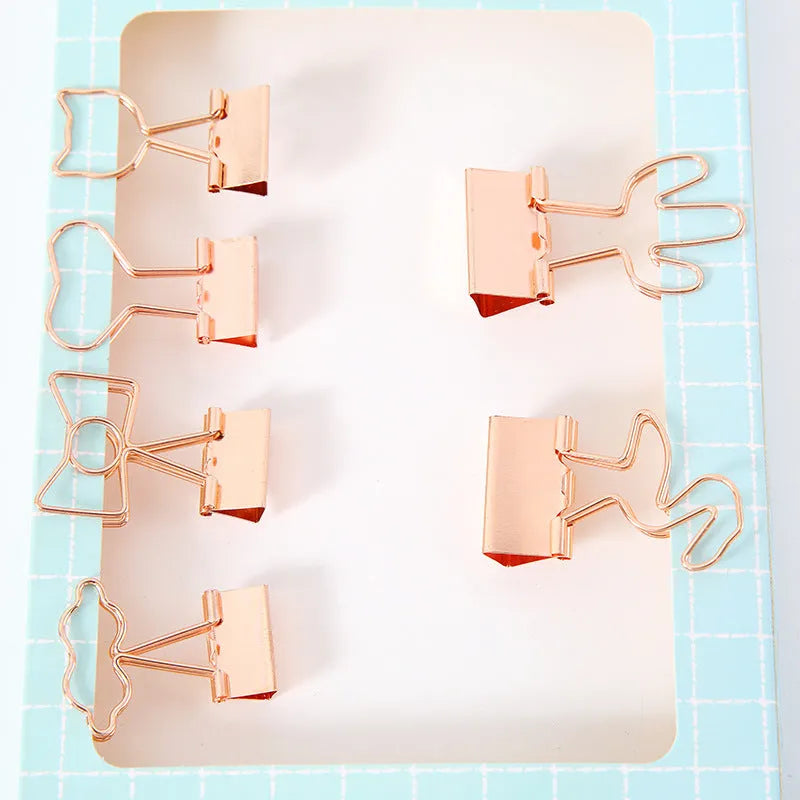 Small gold metal office clip with long tail, showing flamingo, love, cloud, cat, cactus, and bow shape options.