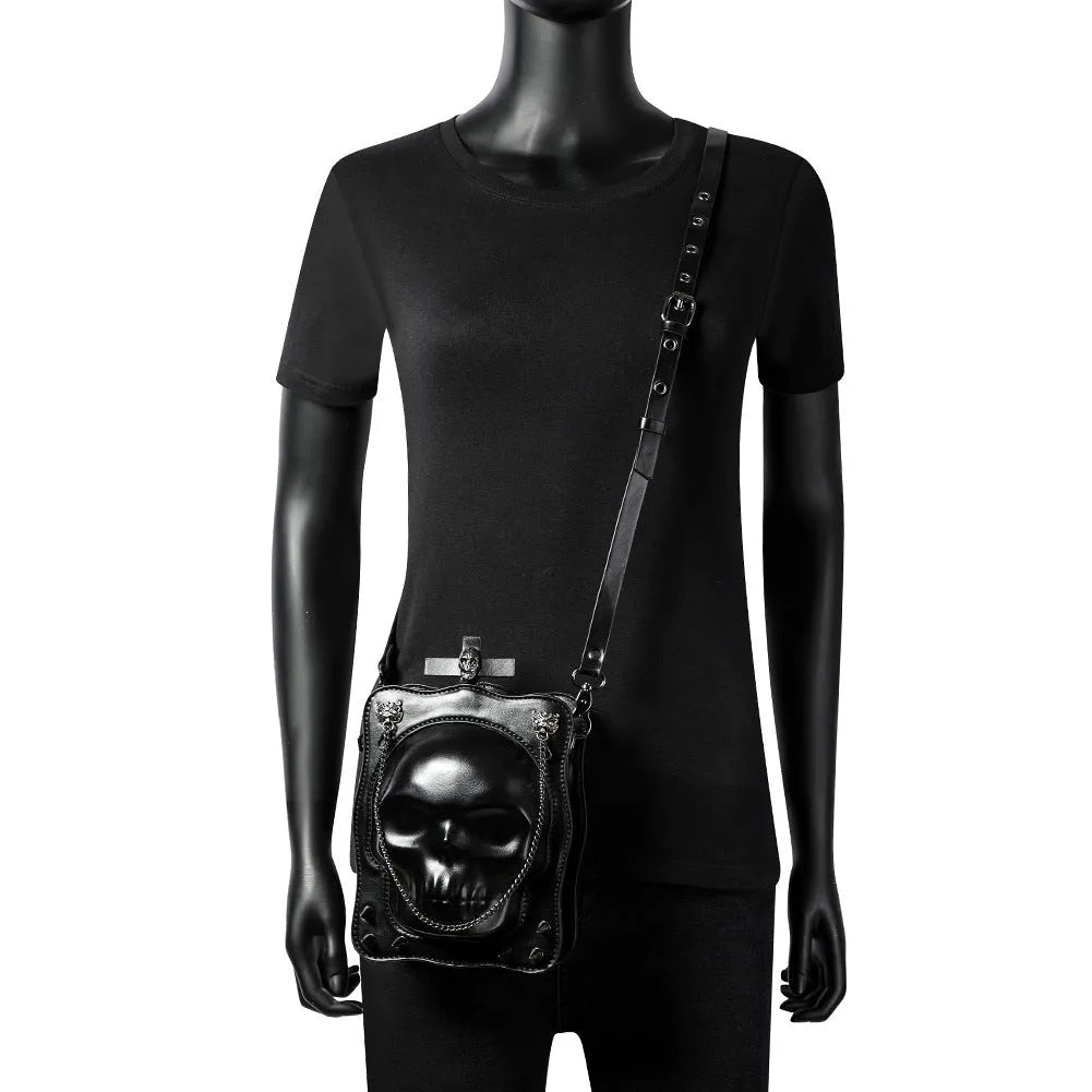 Black vertical square PU leather crossbody bag with embossed skull design, stitching, rivets, and a chain strap.