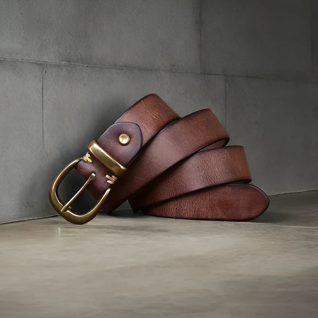 Men's brown casual leather belt with a copper pin buckle on a textured background.