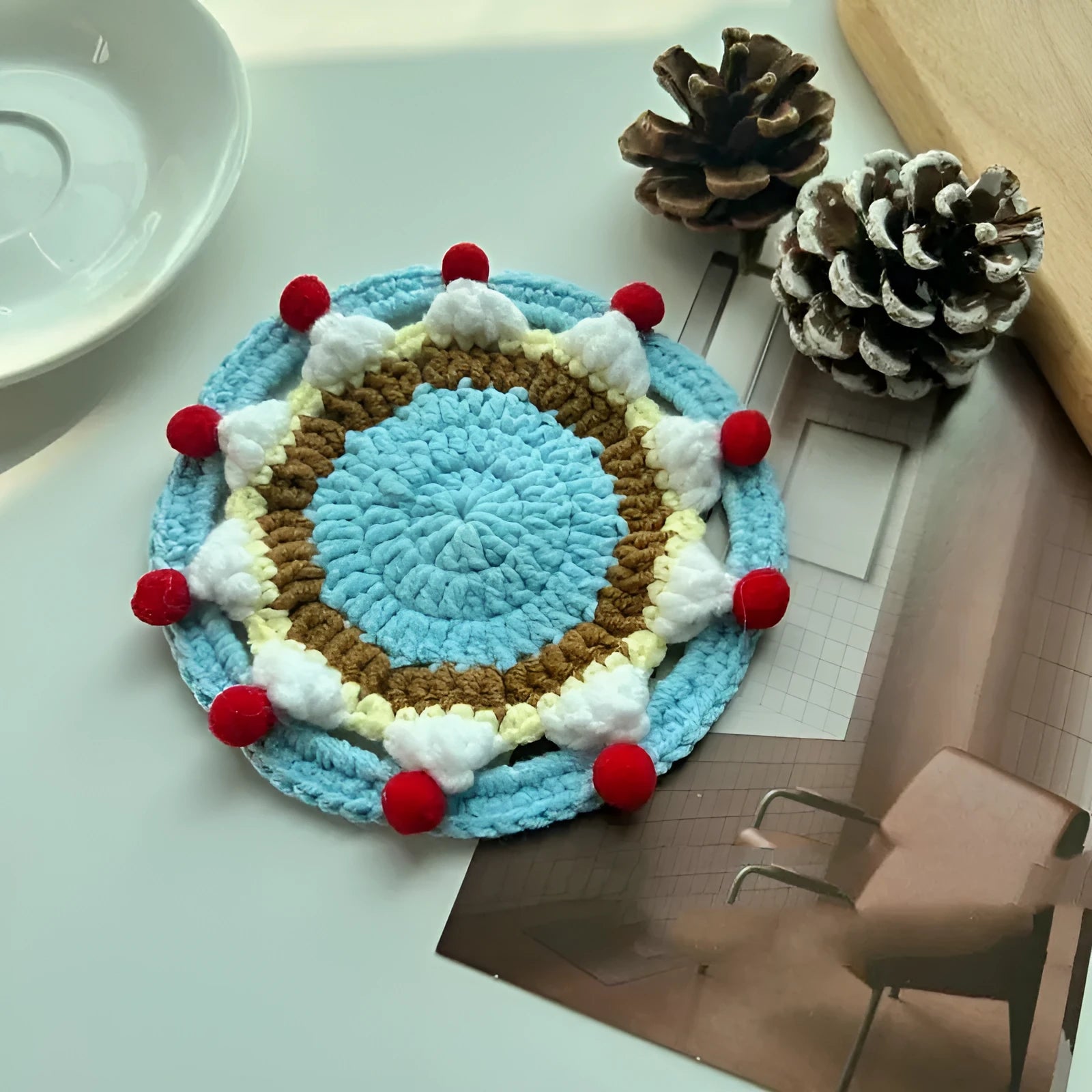 A single 9cm round wool coaster and its decorative cake-themed storage bag.