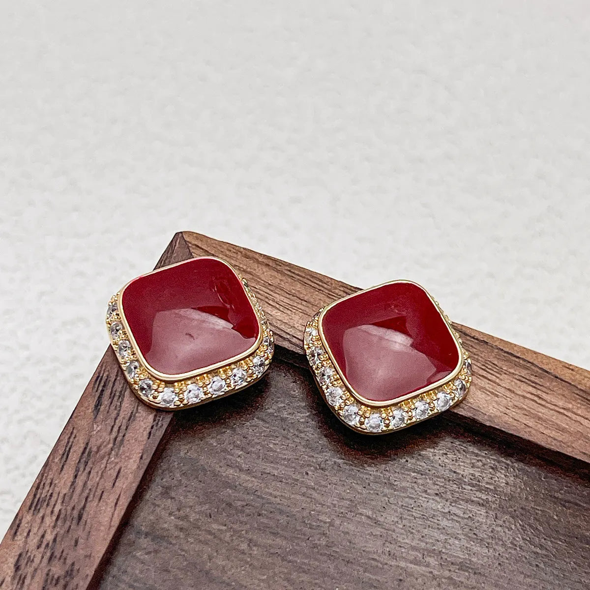 A pair of red geometric square alloy earrings with an inlaid plate design, showing front view.