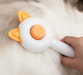Greenish white cat grooming brush with stainless steel teeth and a self-cleaning button on the handle.